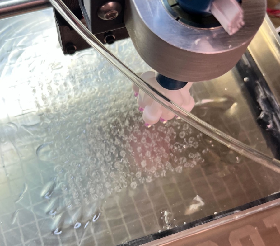 Printer head above a large gel container filled with printed skeins
